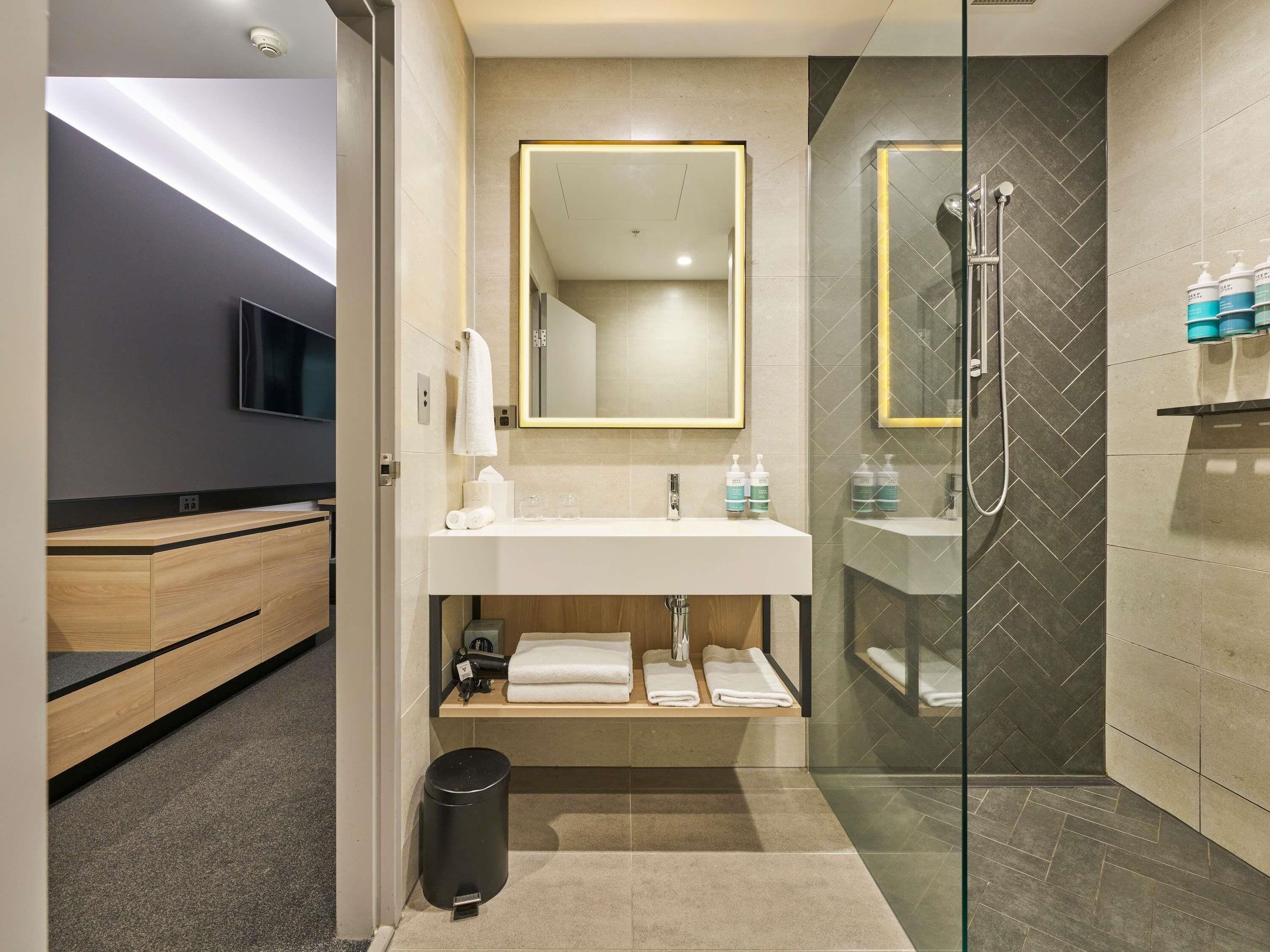 A modern bathroom with a glass shower enclosure, a vanity with a mirror, and a toilet.