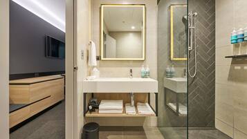 A modern bathroom with a glass shower enclosure, a vanity with a mirror, and a toilet.