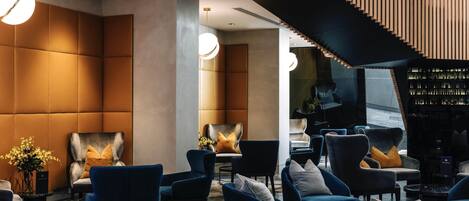 Un vestíbulo moderno con asientos cómodos, una escalera y una zona de bar.