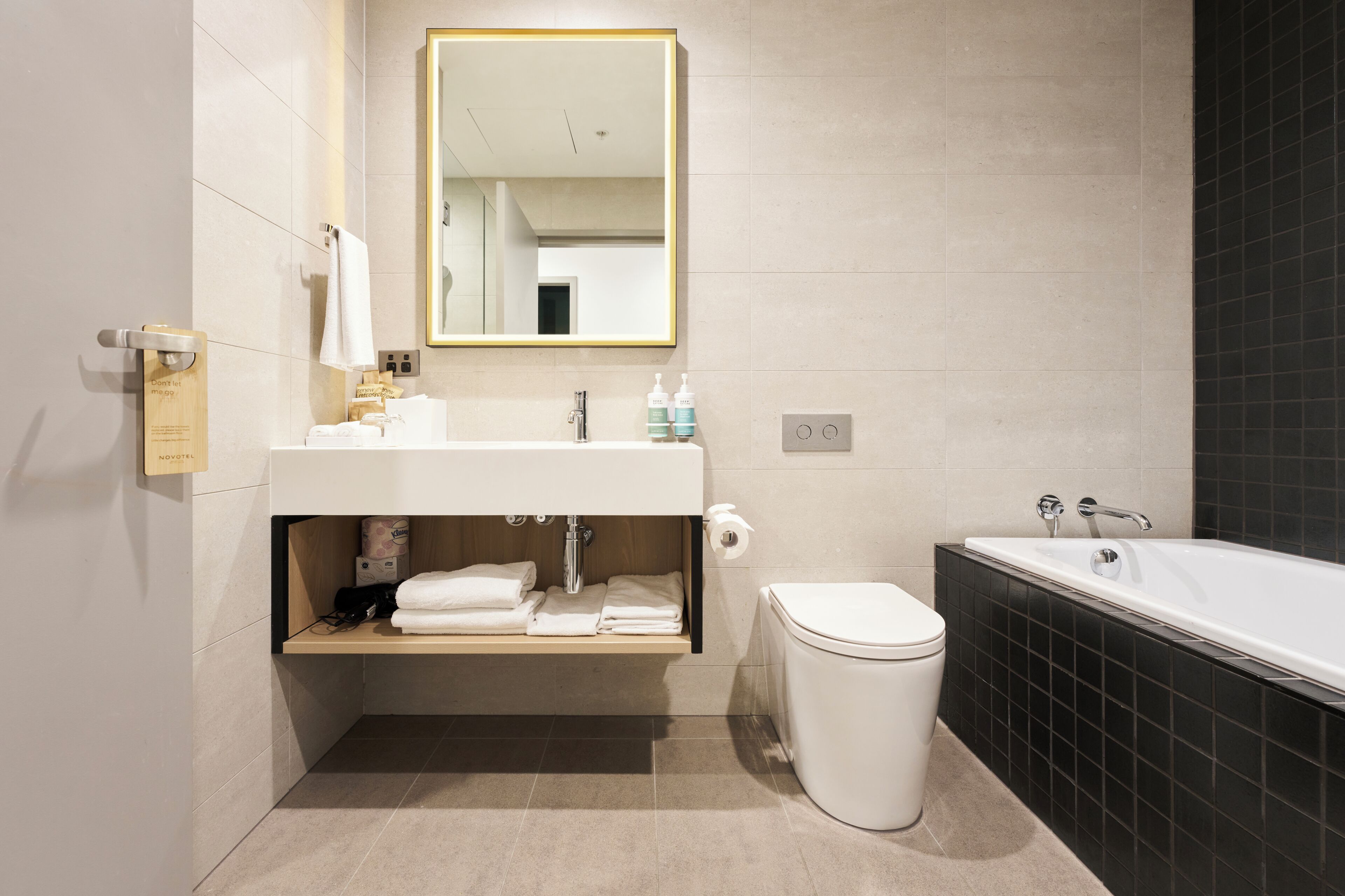 Un baño moderno con lavamanos, espejo y bañera blancos.