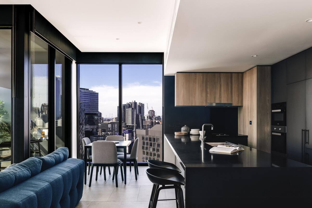 Eine moderne Küche mit Blick auf die Stadt, ein Essbereich mit einer Couch und Stühlen sowie ein großes Fenster.