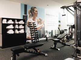 A gym with exercise equipment, a bench, and a wall with a poster.