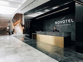 A modern hotel reception area with a marble floor, a reception desk, and a staircase leading to upper floors.