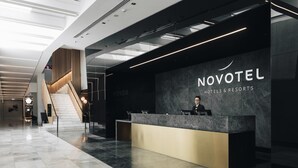 A modern hotel reception area with a marble floor, a reception desk, and a staircase.
