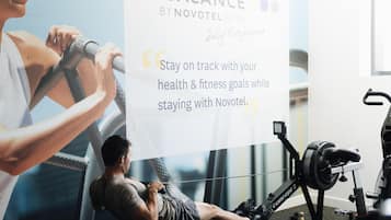 A gym with exercise equipment, a poster with a quote, and a person using a rowing machine.