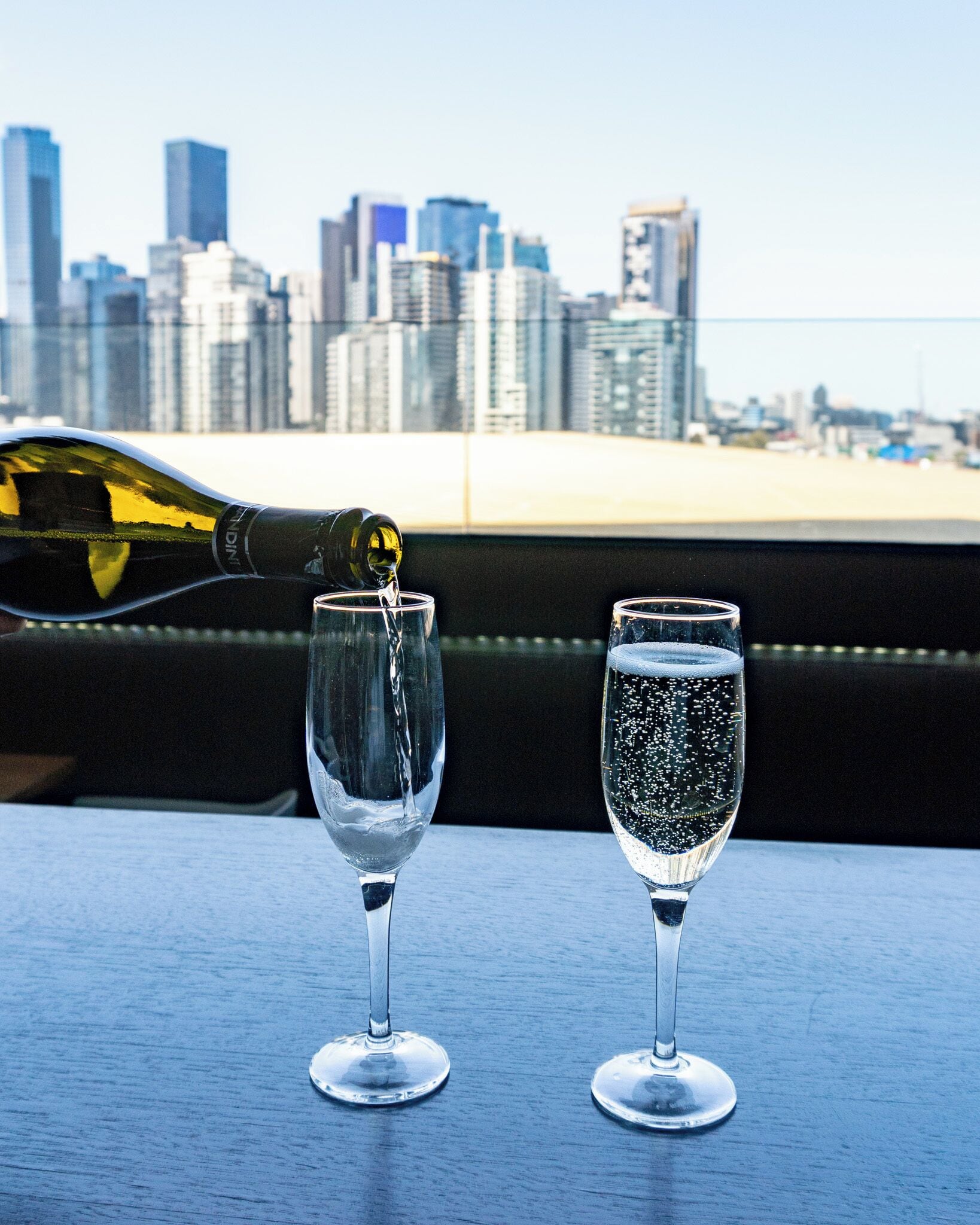 Two glasses on a table with a city skyline in the background.
