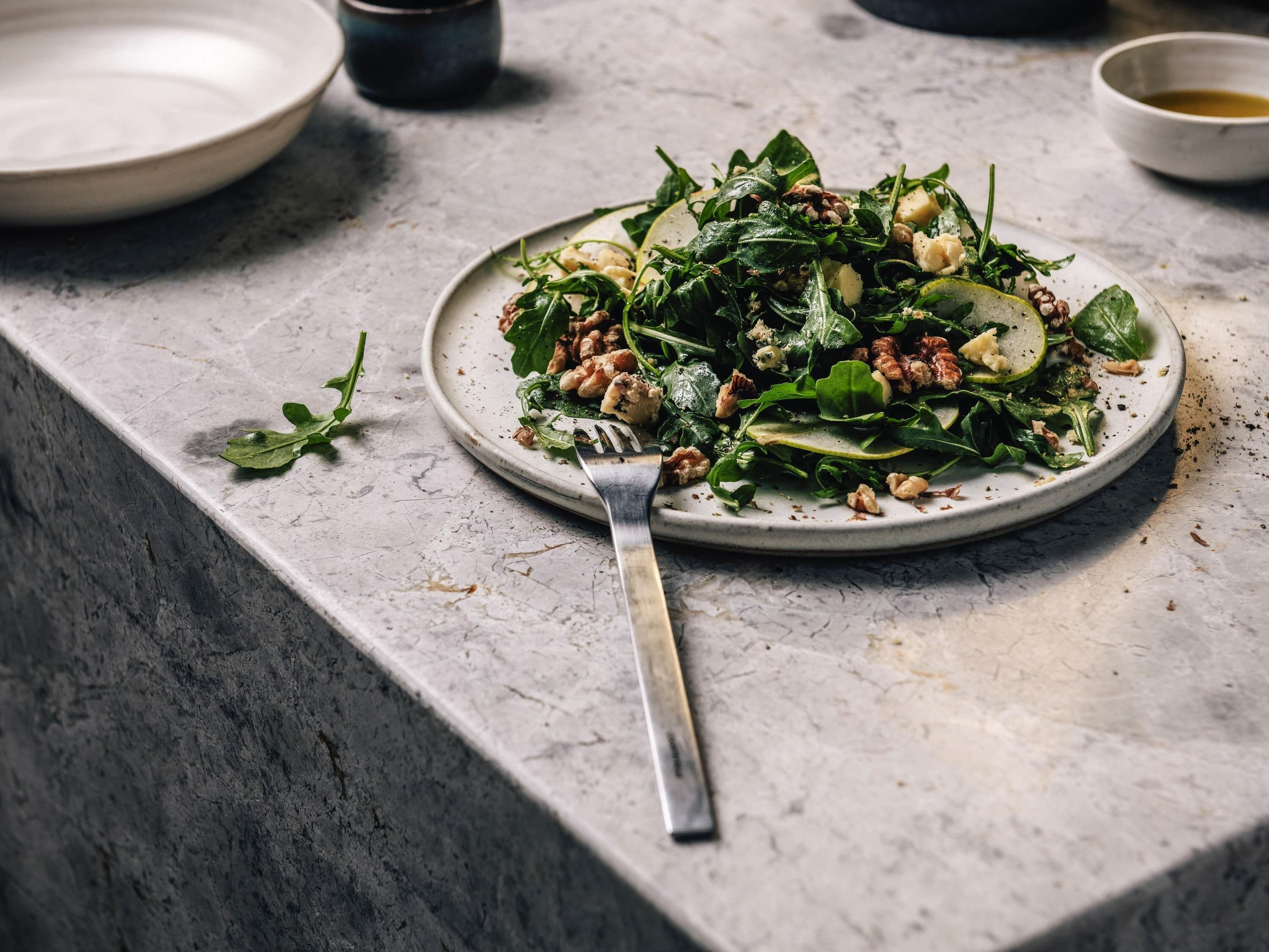Une assiette de salade sur un plan de travail en marbre.