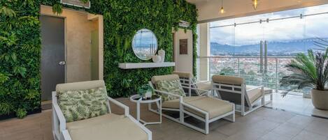 A modern lounge area with a green wall, white furniture, and a city view.