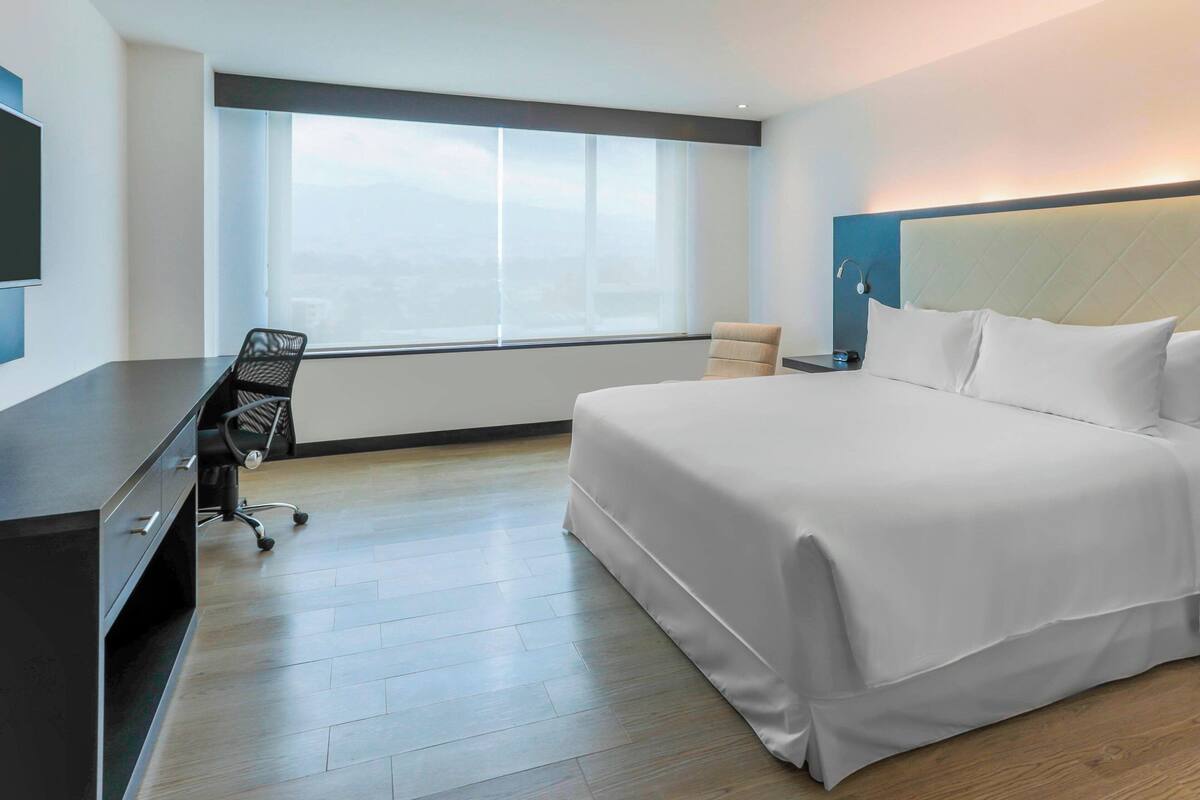 Una habitación de hotel moderna con una cama grande, un escritorio y una silla.