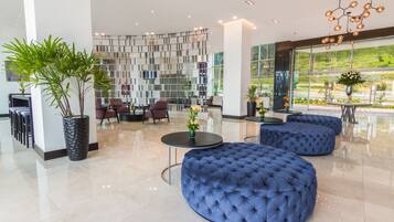 Een moderne lobby met een zithoek, een decoratieve wand en grote ramen.