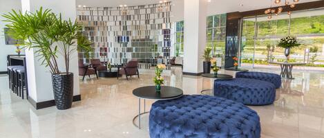 A modern lobby with a seating area, a decorative wall, and large windows.