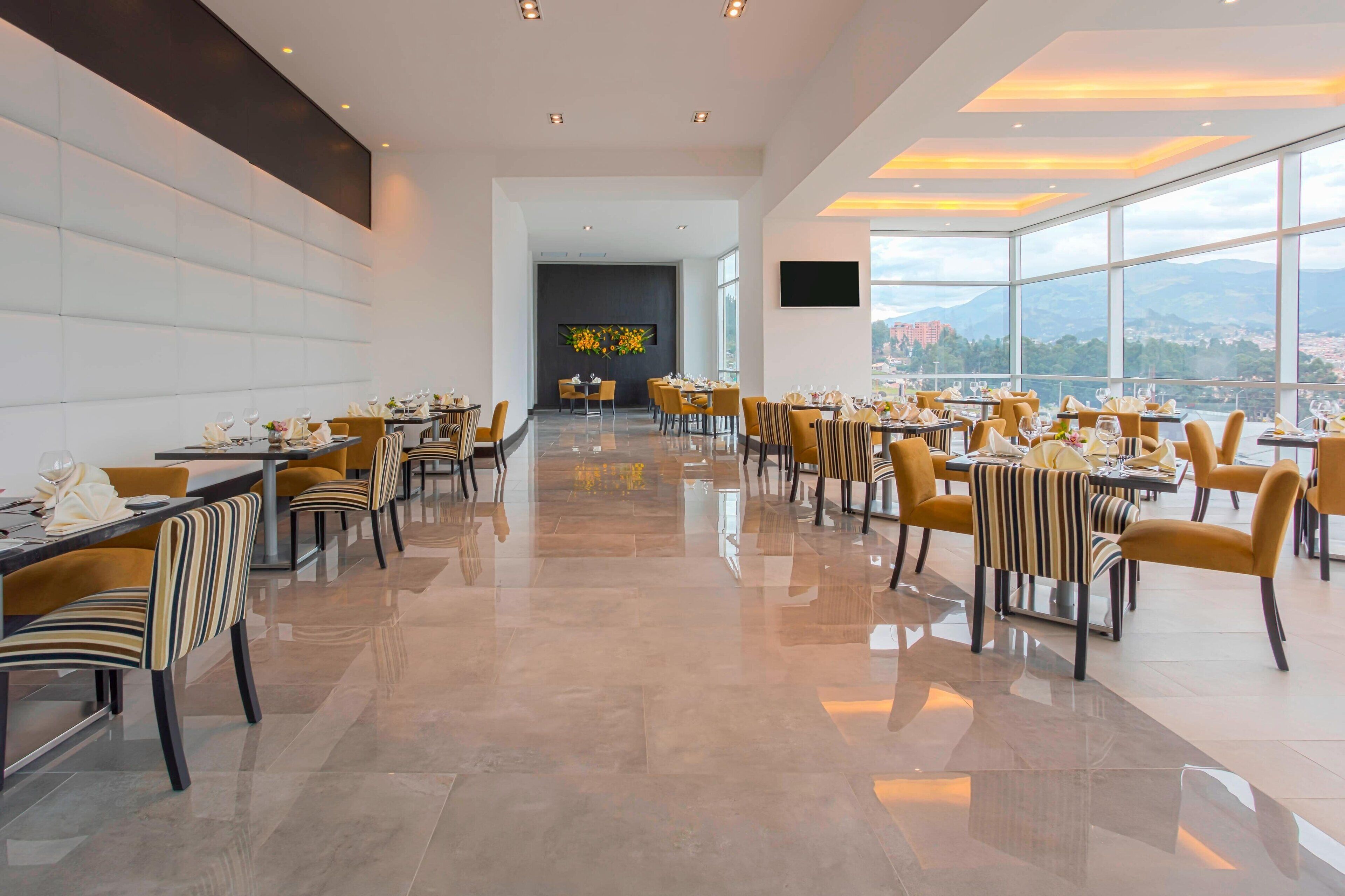 Uma ampla área de jantar com mobiliário moderno e vista para a cidade.