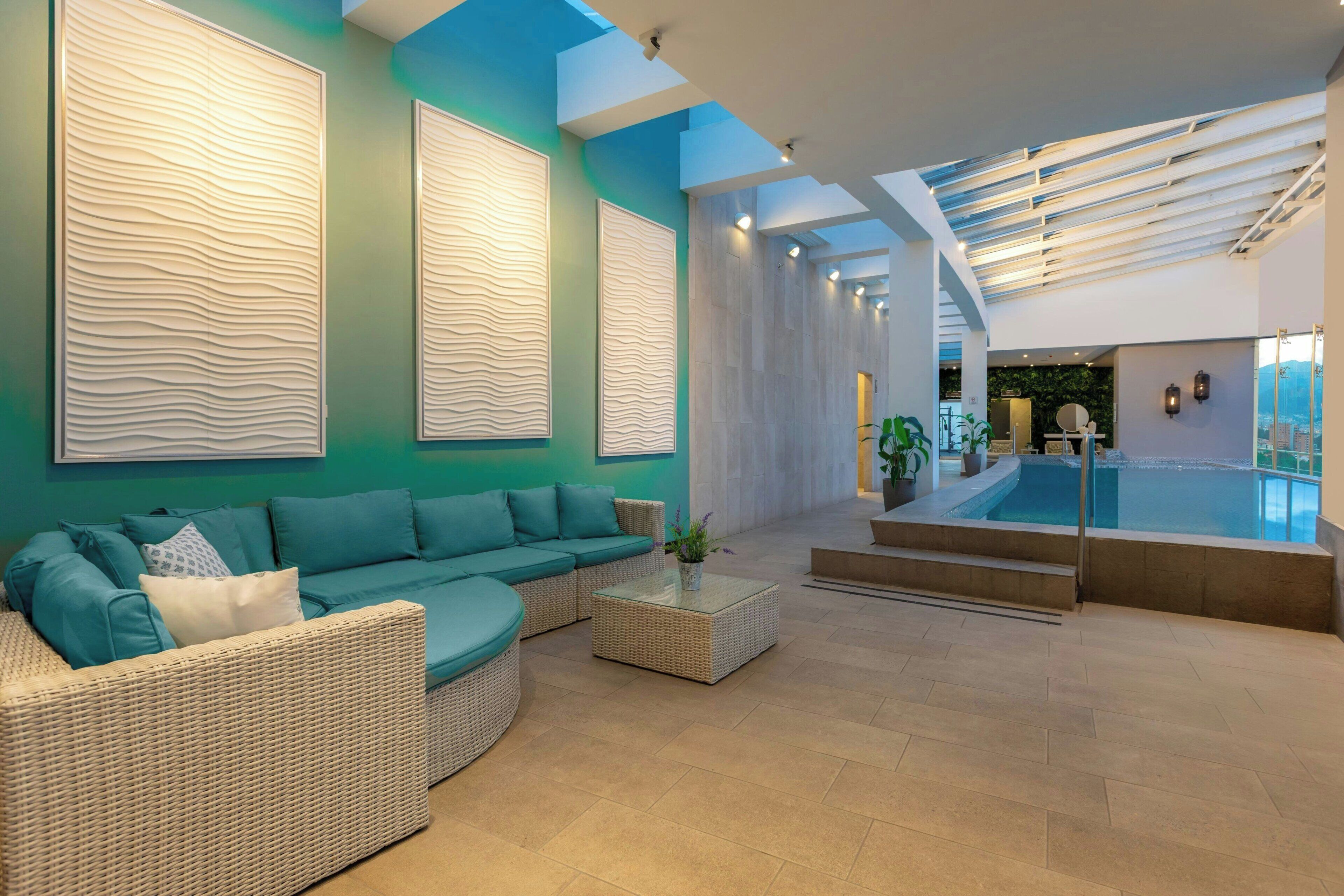 A modern interior with a sectional sofa, a coffee table, and a view of an outdoor pool area.