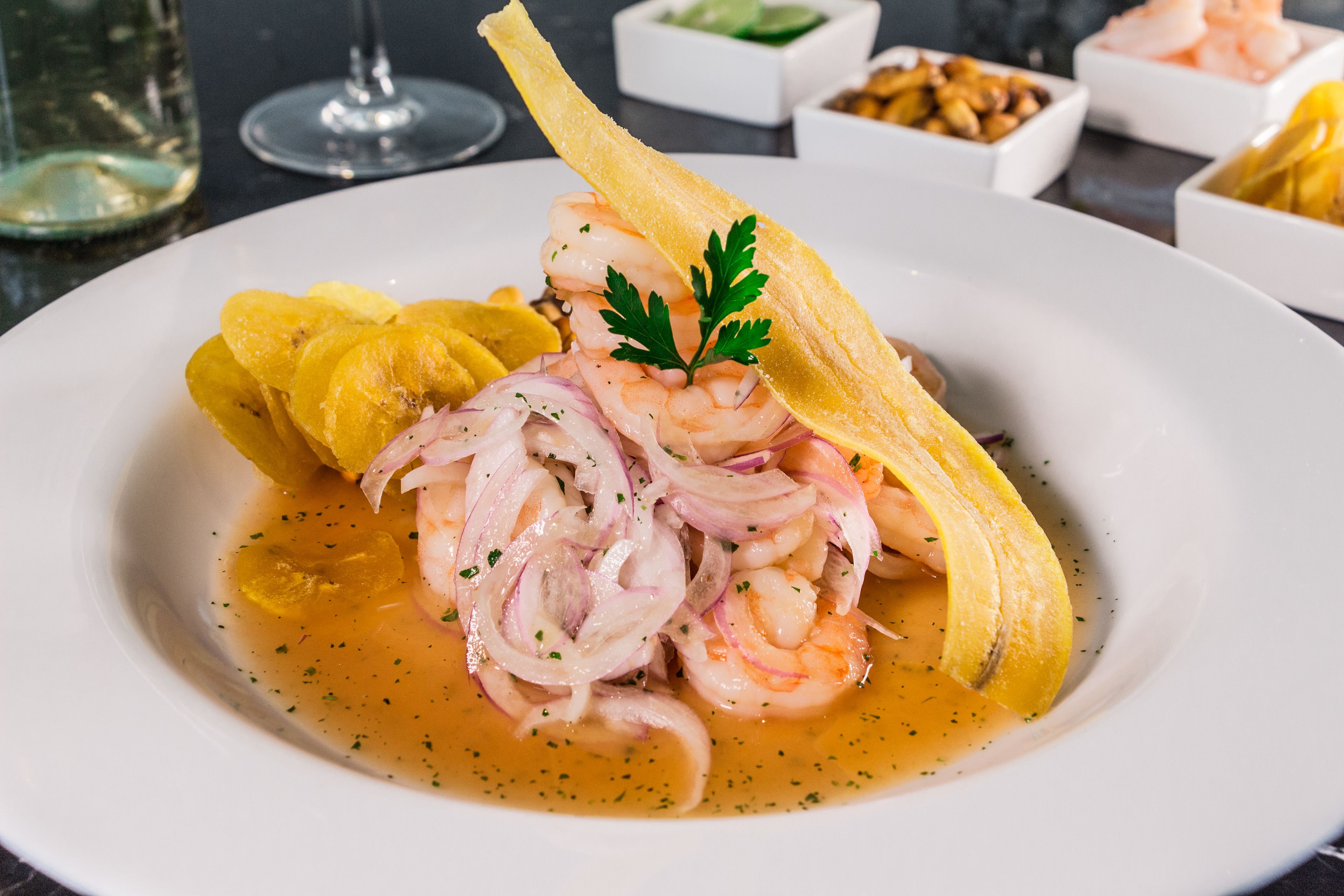 Un plato de ceviche con camarones, cebolla y una tajada de plátano.