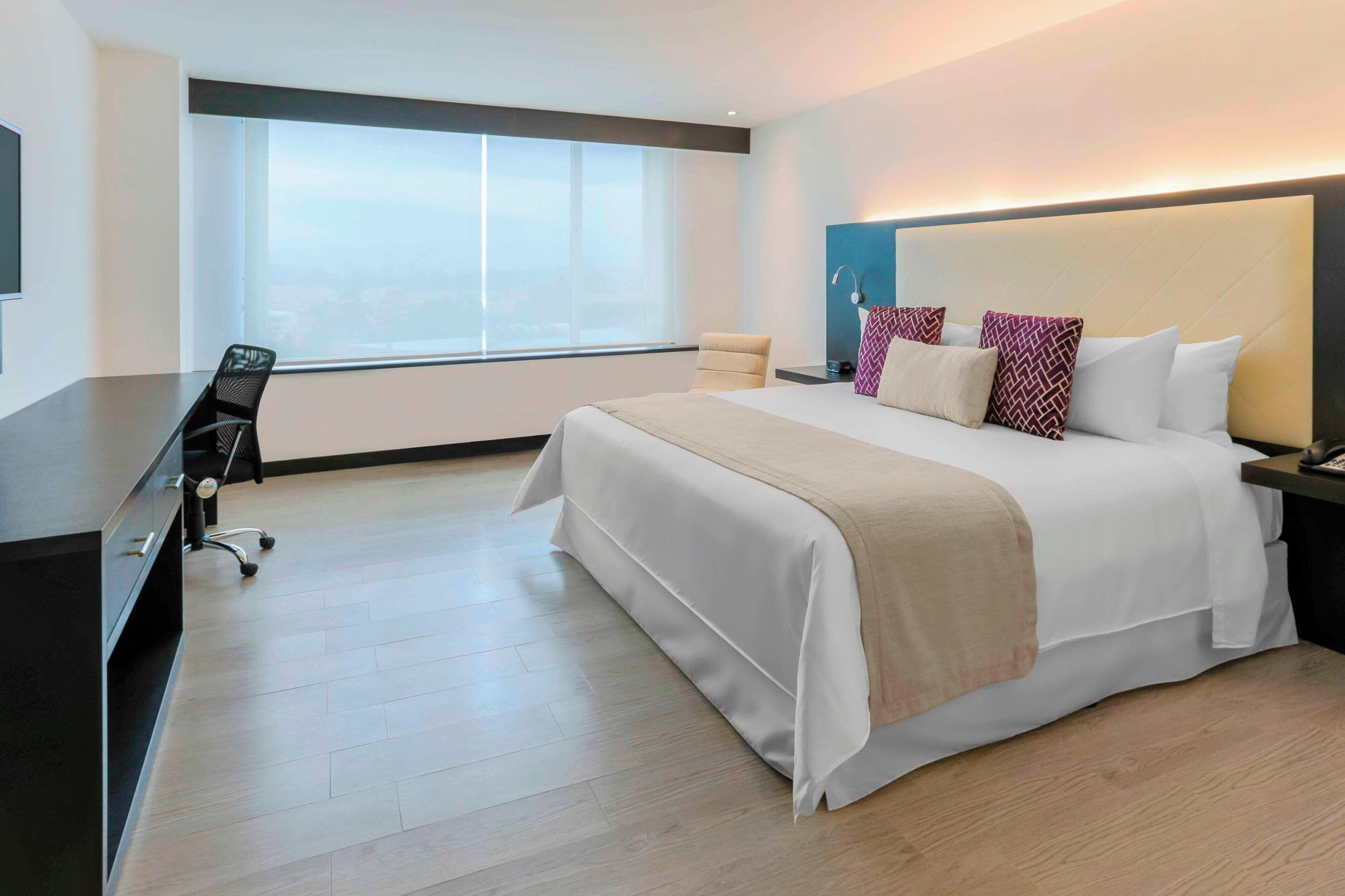 Una habitación de hotel con una cama grande, un escritorio y una silla.