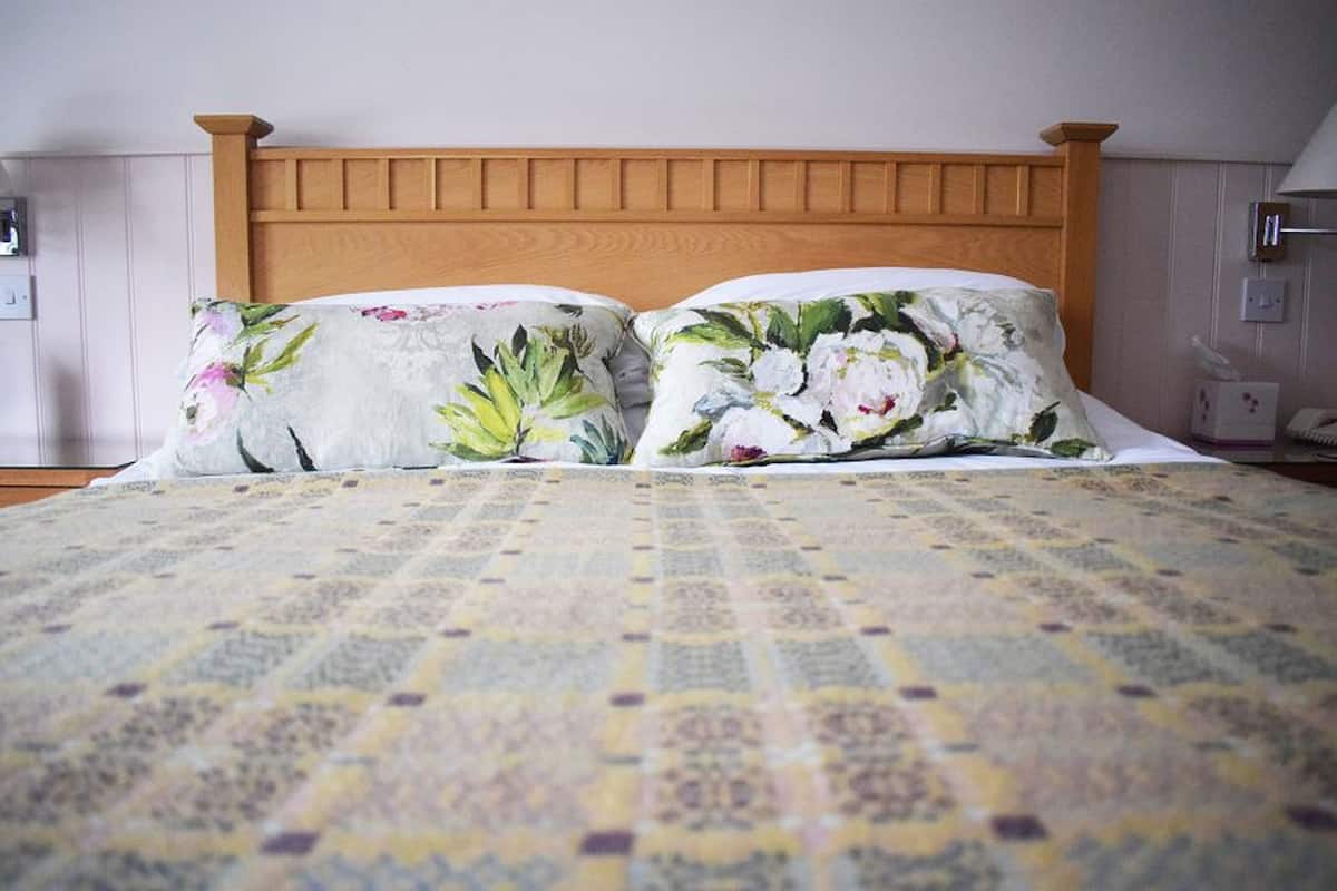 A bed with a floral-patterned pillow and a patterned bedspread.