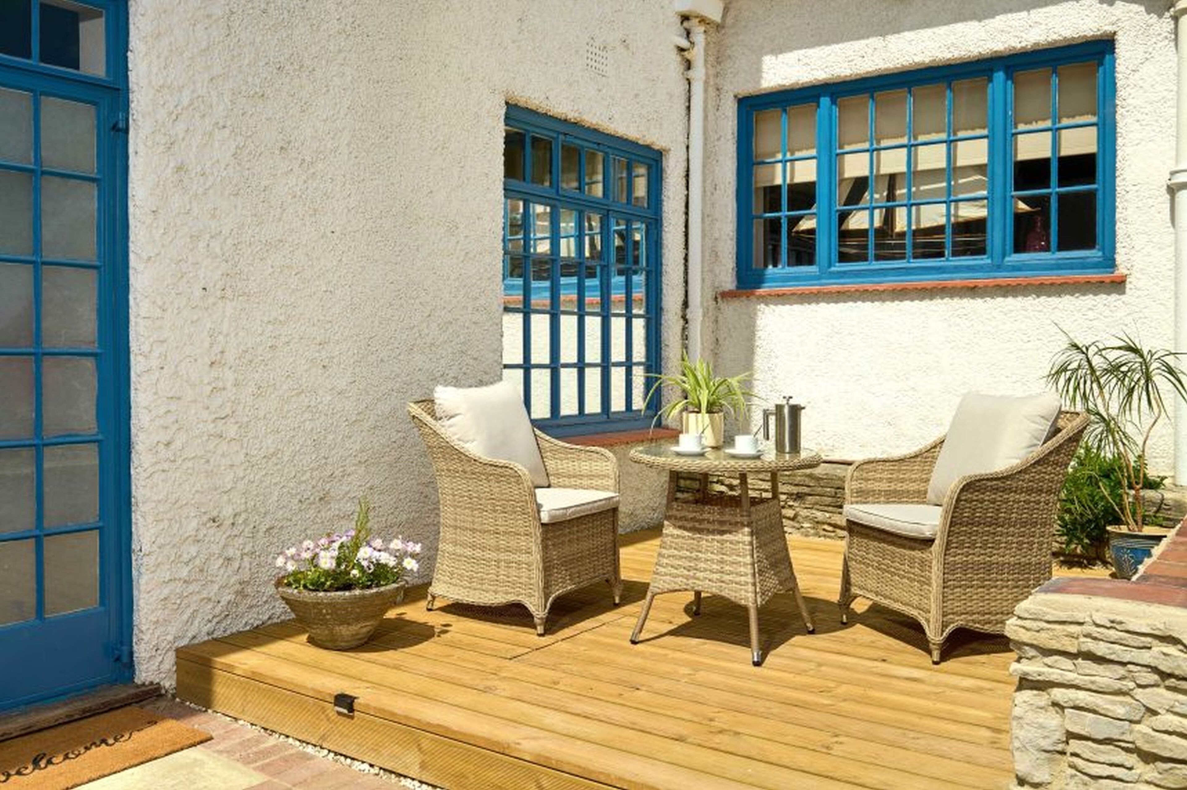 A patio with wicker furniture, a small table, and potted plants.