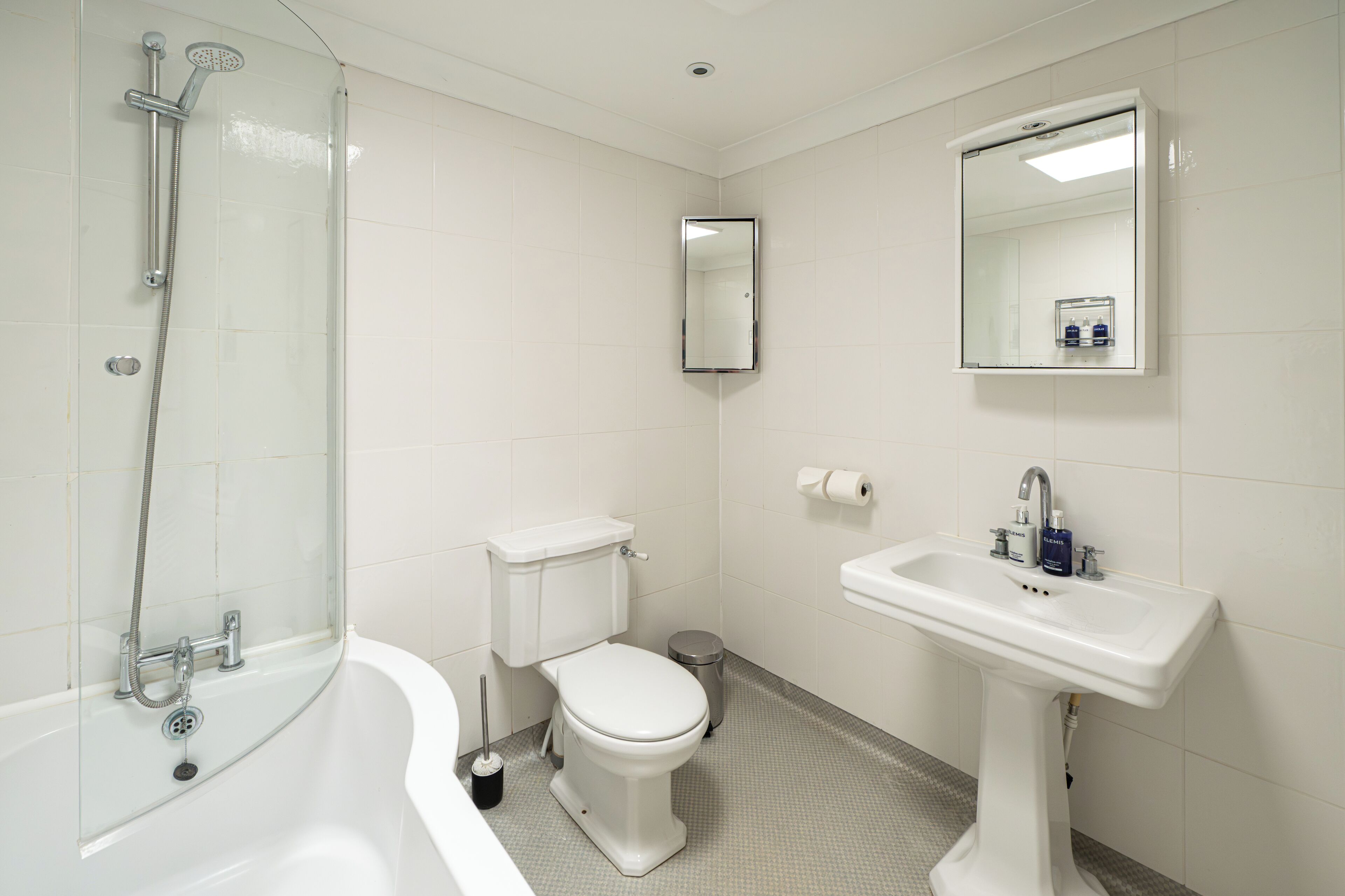 A bathroom with a bathtub, toilet, sink, and mirror.