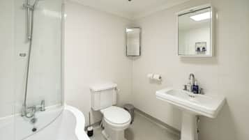 A bathroom with a bathtub, toilet, sink, and mirror.