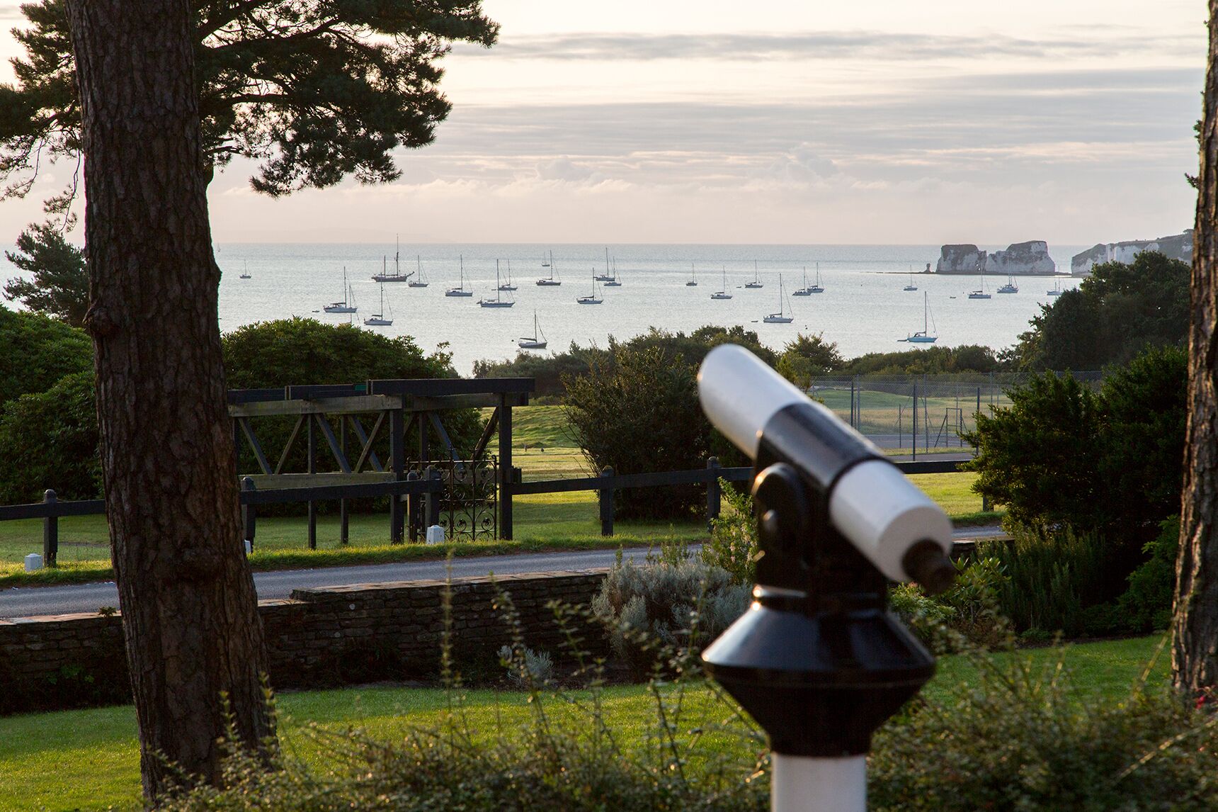 A telescope overlooking a coastal area with sailboats and cliffs.