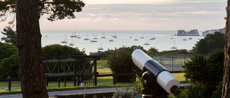 A telescope overlooking a coastal area with sailboats and cliffs.