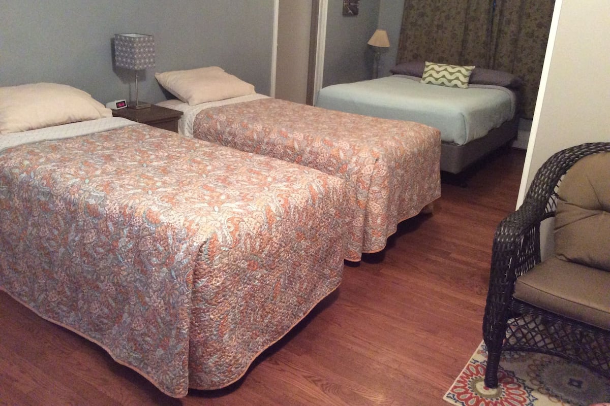 A hotel room with two beds, a chair, and a nightstand with a lamp.