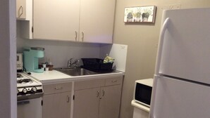 Cocina compacta con estufa, fregadero y refrigerador.