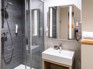 Un baño moderno con cabina de ducha de vidrio, lavabo blanco y espejo.