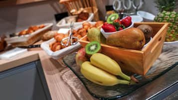Un buffet proposant une variété de fruits, de viennoiseries et de pains.