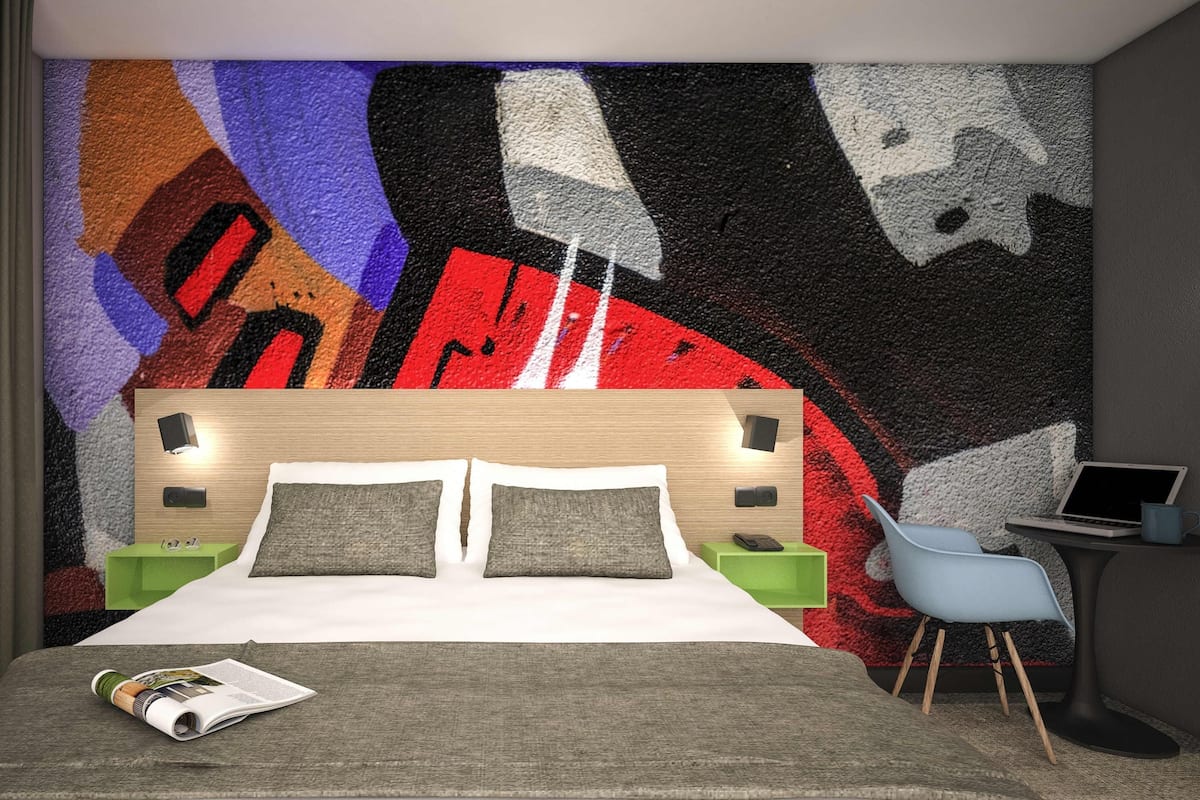 Een slaapkamer met een bed, nachtkastjes, een bureau en een stoel.