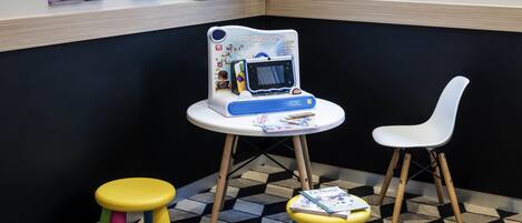 A children's play area with a small table, two stools, and a white chair.