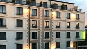 Ein mehrstöckiges Hotel mit Balkonen, beleuchteten Fenstern und einem grünen Schild auf der rechten Seite.