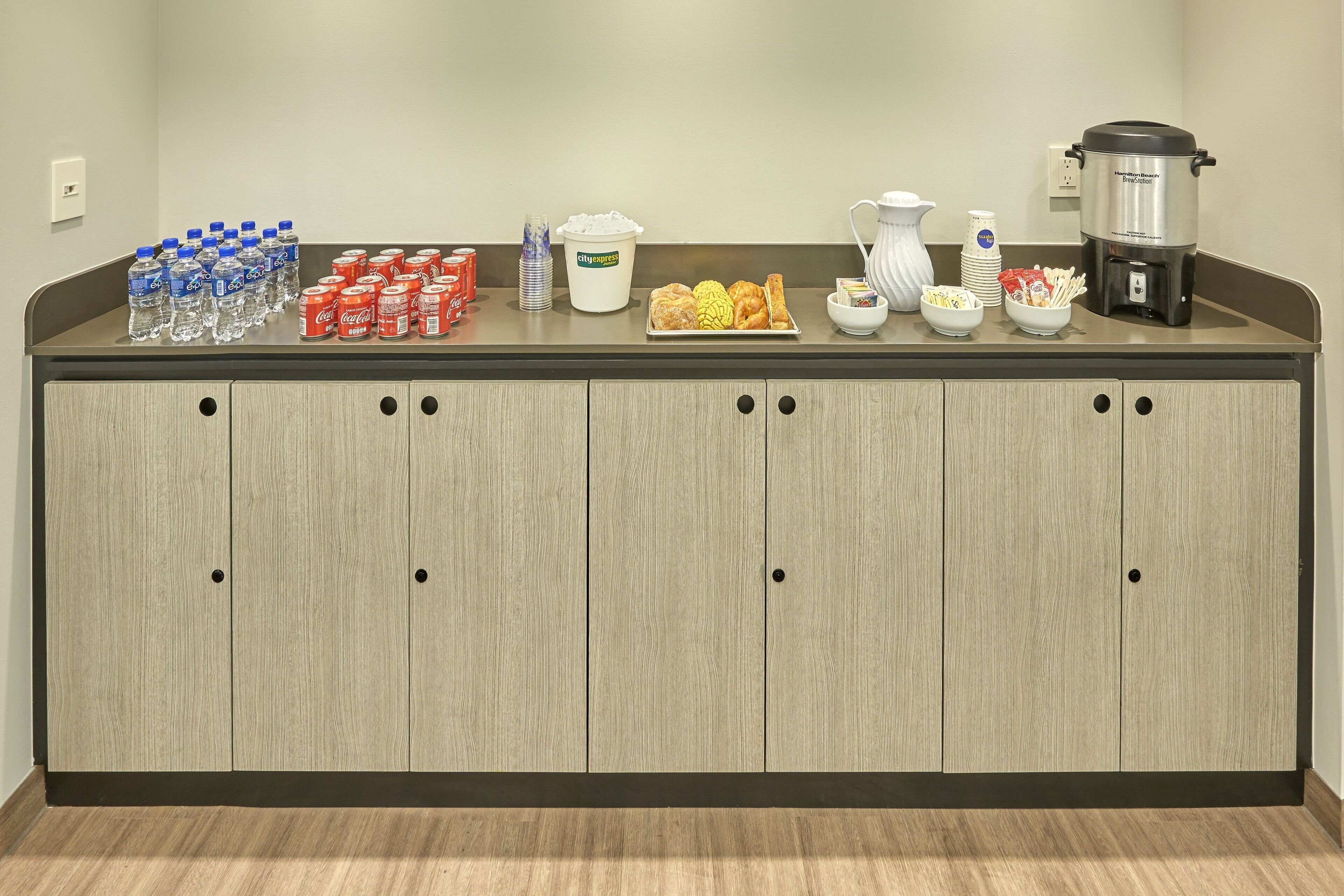 A kitchen counter with water bottles, a coffee maker, and a slow cooker.
