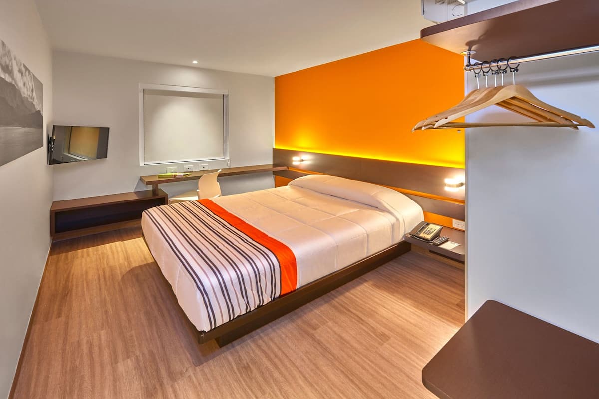 A modern hotel room with a bed, bedside table, and a wall-mounted TV.