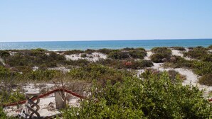 A beach view with a wooden structure and a table, surrounded by vegetation. - Escape Beach House (Bergrivier)