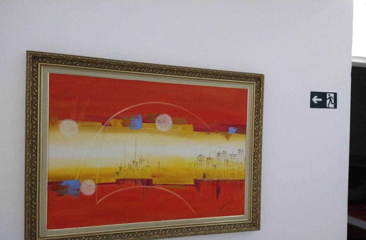 Ein gerahmtes, abstraktes Gemälde an einer weißen Wand.