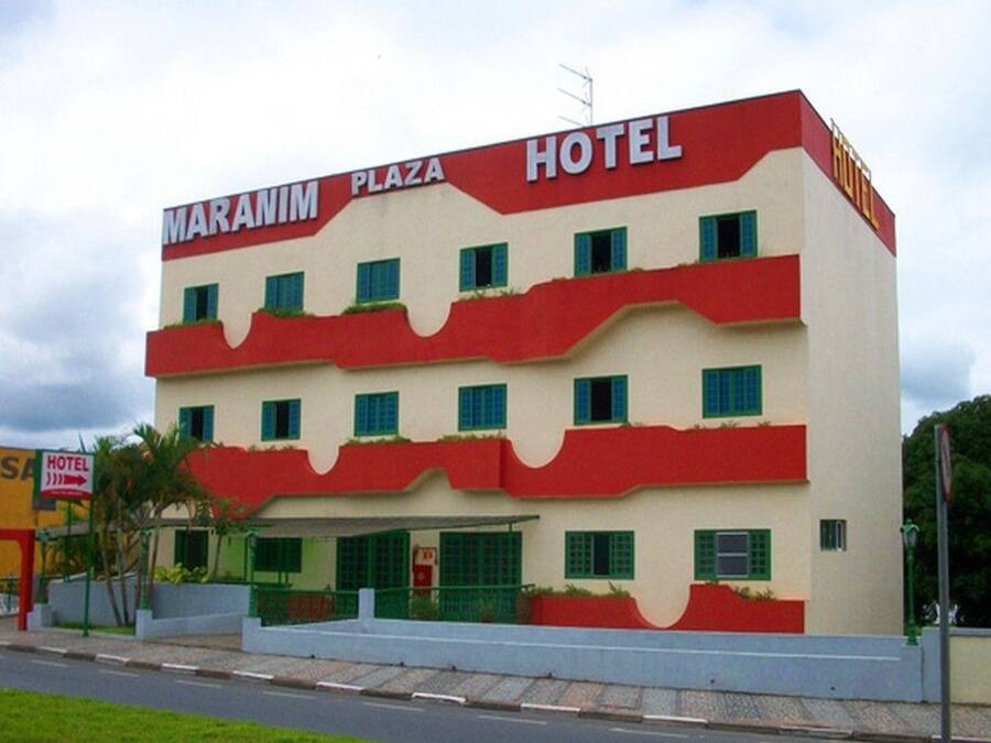 A multi-story hotel with a red and white facade, multiple windows, and a sign indicating it is a hotel.