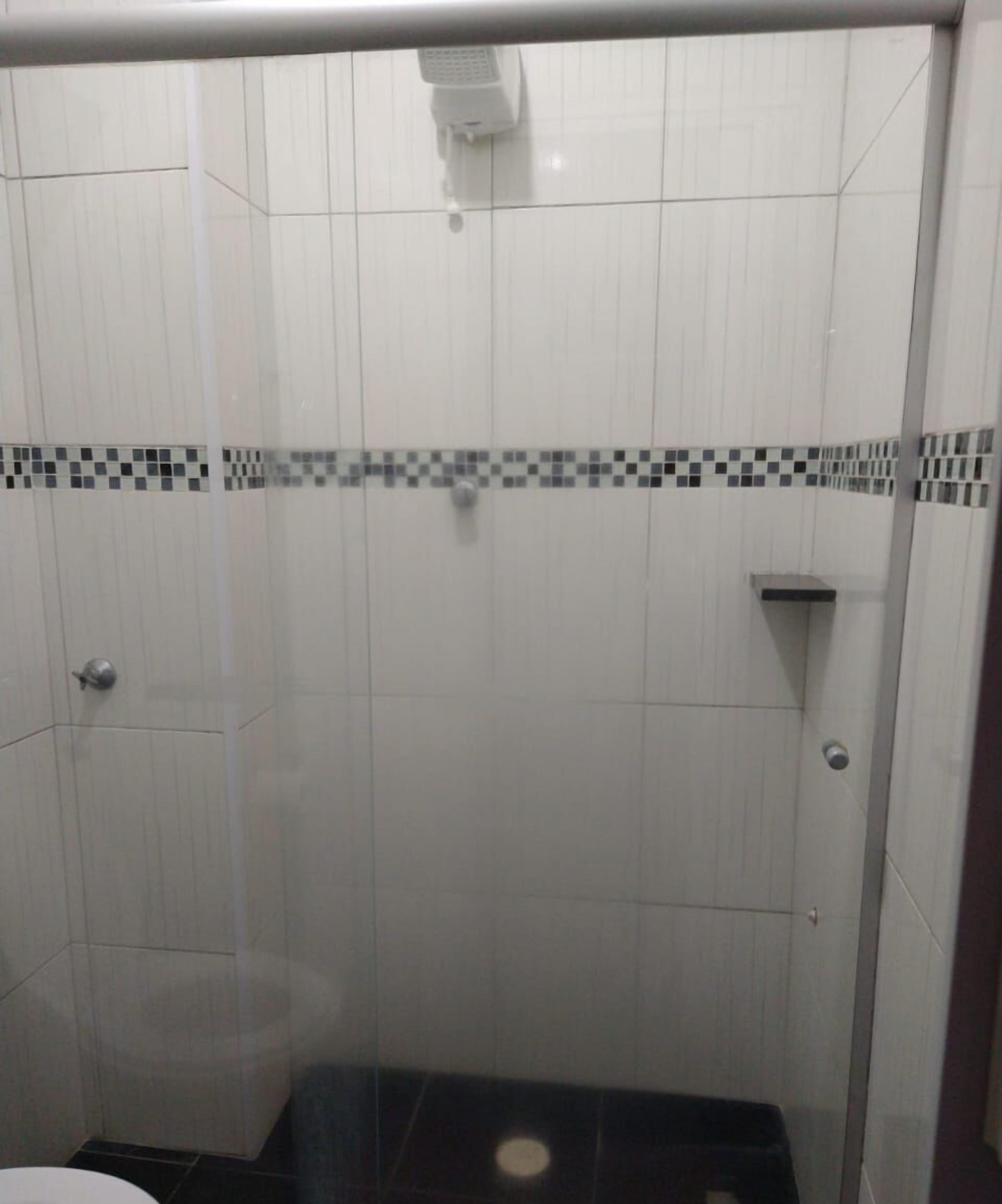 En dusch med vita kakelplattor och en svartvit kakelram.