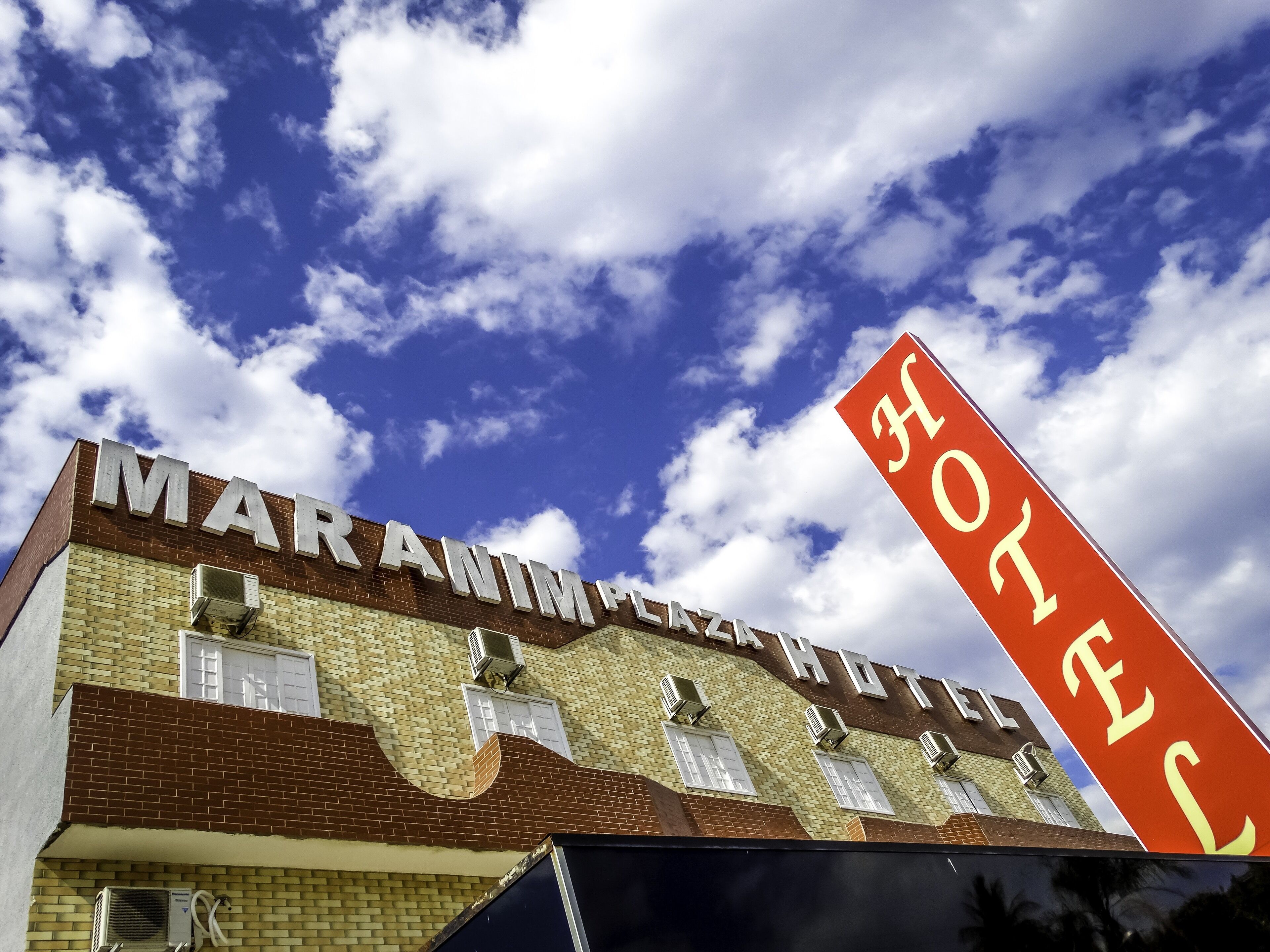 A hotel named "MARABIMPLAZA HOTEL" with a clear view of the sky and clouds.