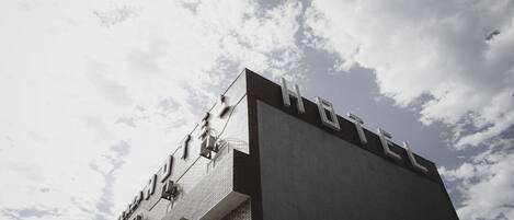 Un hotel con un diseño arquitectónico moderno, que presenta un llamativo letrero con la palabra 'HOTEL' en la fachada.