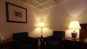 A hotel room with two armchairs, a small round table, a lamp, and a framed picture on the wall. - Motel Chez Nous (Laval)