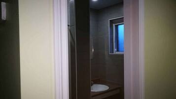 A bathroom with a white sink, a window, and a shower.