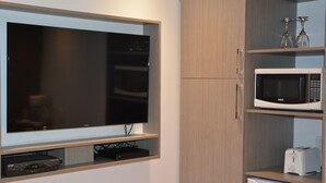 A modern kitchen with a built-in microwave, toaster, and wine glasses on the shelf. - Motel Chez Nous (Laval)