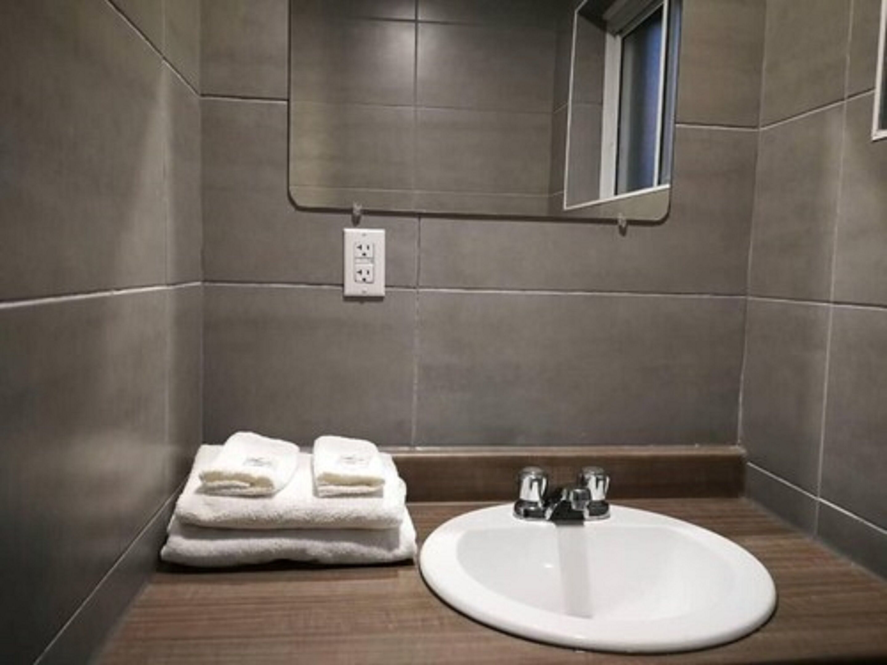 Un baño con un lavamanos blanco, dos toallas y un espejo en la pared.