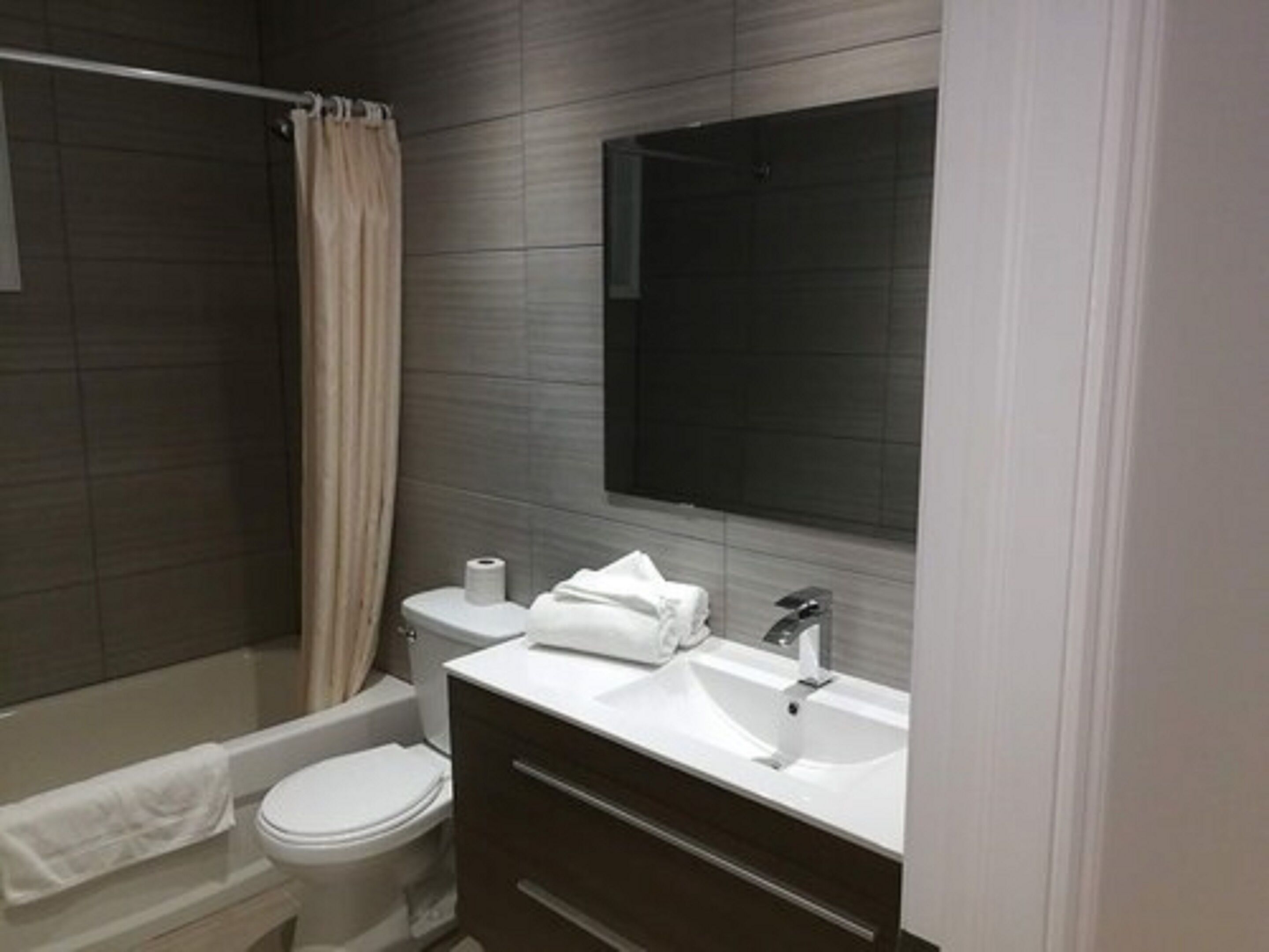 Un baño moderno con bañera, inodoro y tocador con espejo.