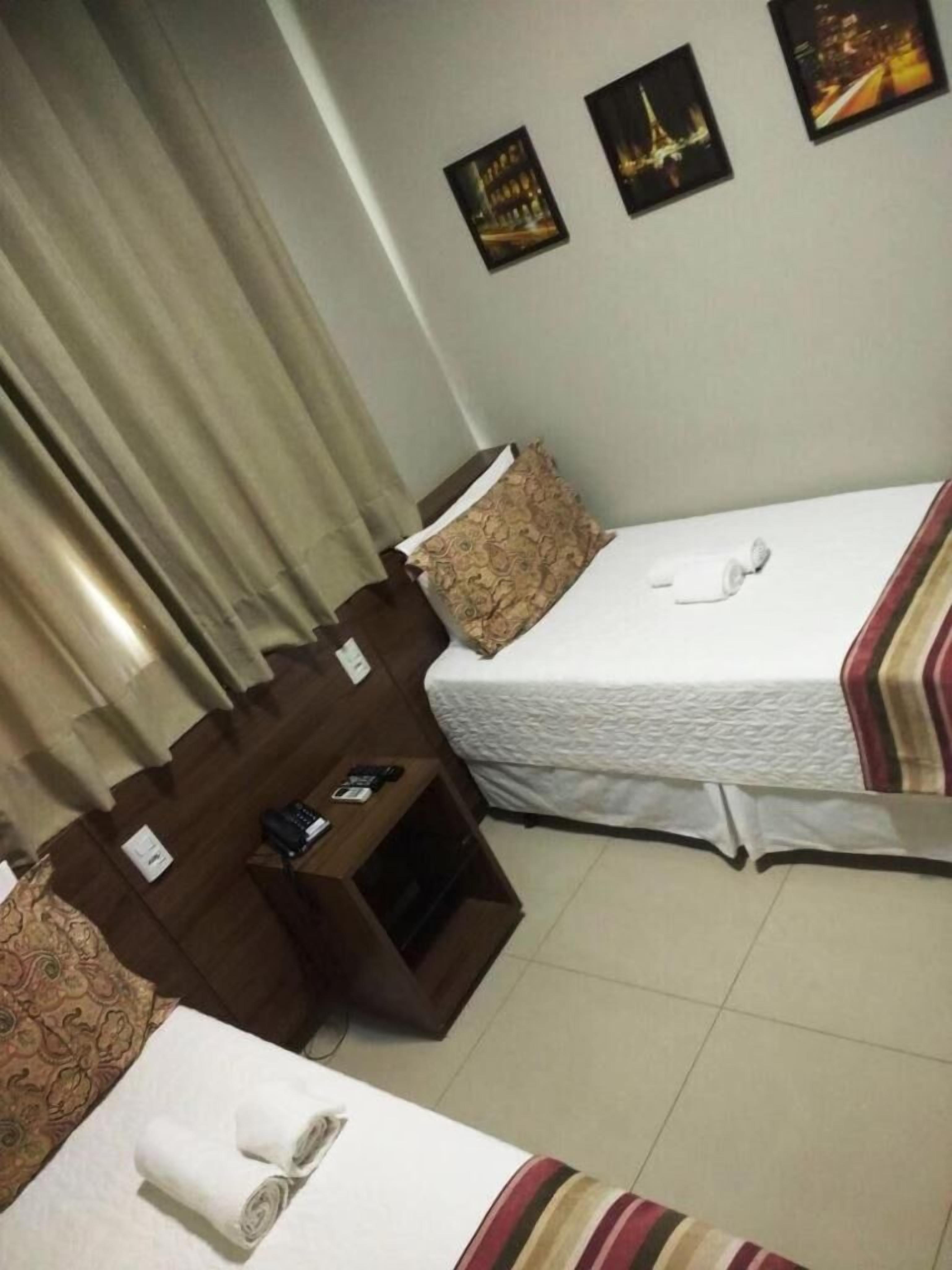 Une chambre d’hôtel avec deux lits, une table de chevet en bois et une petite table.