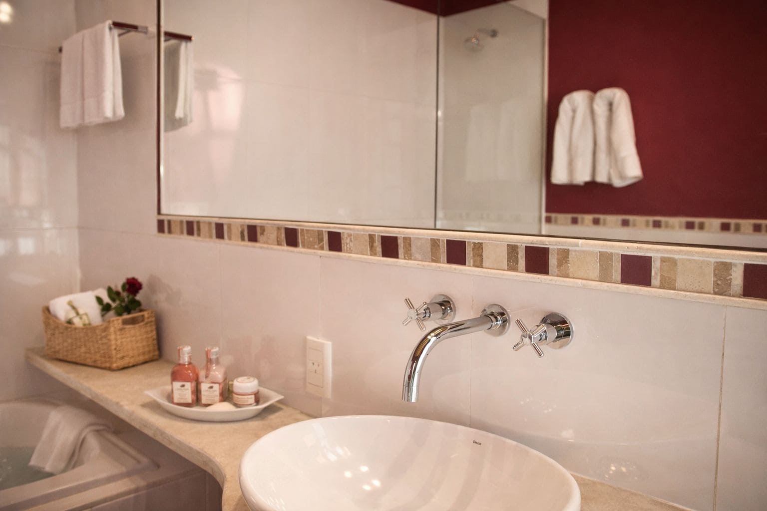 A bathroom with a large mirror, a white sink, and a shower.