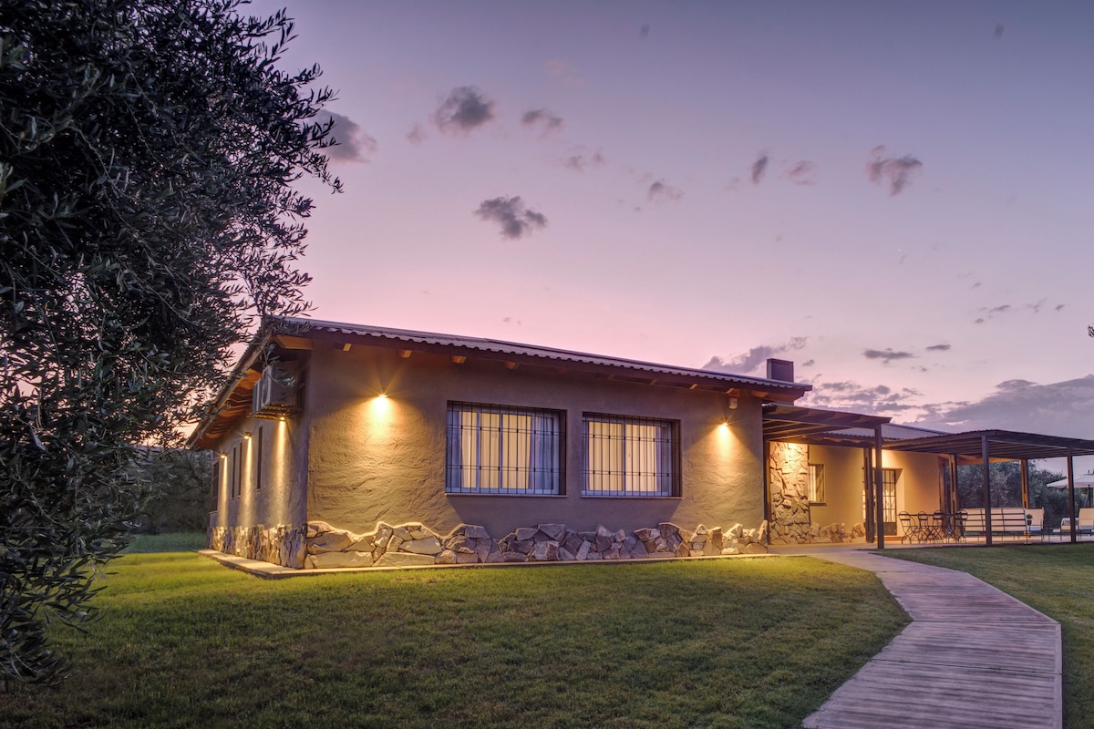 A modern house with a stone foundation, a covered patio, and a well-maintained lawn.