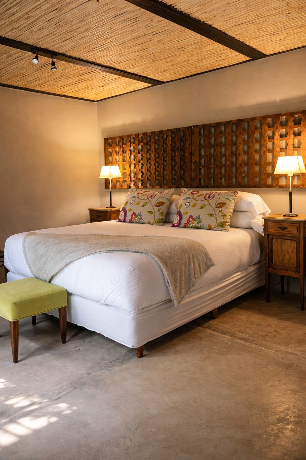 A bedroom with a bed, bedside tables, a bench, and a wooden headboard.