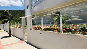 A modern building with a balcony featuring a variety of colorful flowers. - Apartamento Nobre da Praia dos Ingleses (Florianópolis)